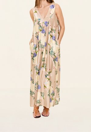 Ærmeløs beige maxikjole med blå og hvide blomsterprint, V-hals, lommer, båret med brune remsandaler med flad sål.