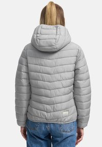Grijze pufferjack met een capuchon, voorzien van een chevronpatroon, zachte textuur, elastische manchetten en een label op de onderrug.