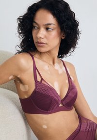 Plum underwire bra with mesh accents, featuring curved cups, adjustable straps, and a textured band design.