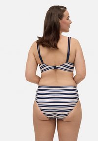 Top y parte inferior de bikini a rayas en colores marino y crema. Tejido suave con tirantes ajustables y cierre de gancho en la parte posterior.