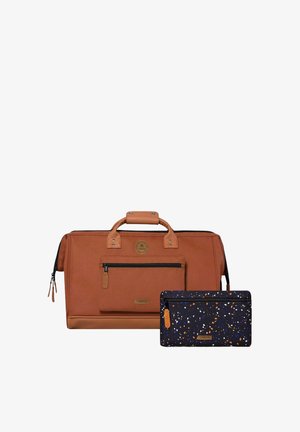 Sac de voyage en cuir marron et tissu avec poche avant et pochette zippée noire tachetée avec des accents orange et bleus.