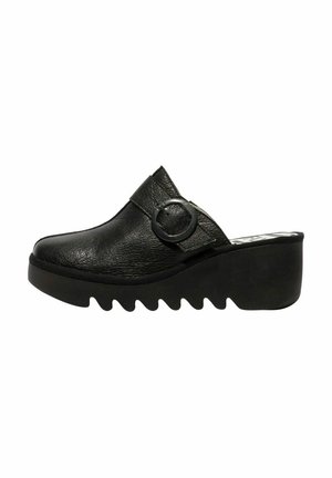 Zoccoli in pelle nera con una fascia larga e accessori circolari, caratterizzati da una superficie testurizzata e una suola spessa e irregolare.