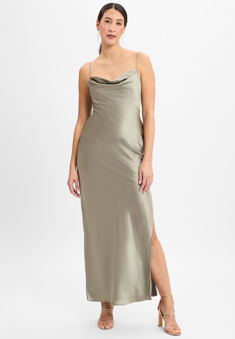 Satin Abendkleid in olivgrün mit einem Cowl-Ausschnitt, dünnen Trägern und einem seitlichen Schlitz. Das Model trägt schlichte Riemchen-Heels und präsentiert eine elegante Silhouette.