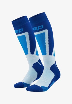 Kompressionssocken in Blau und Weiß. Mit Farbverlauf, geometrischen Mustern und Logo. Knielang mit strukturierten Sohlen.