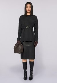 Pullover a maniche lunghe in maglia nera con vita aderente, gonna a tubino in pelle nera, stivali neri al ginocchio e borsa in pelle marrone.