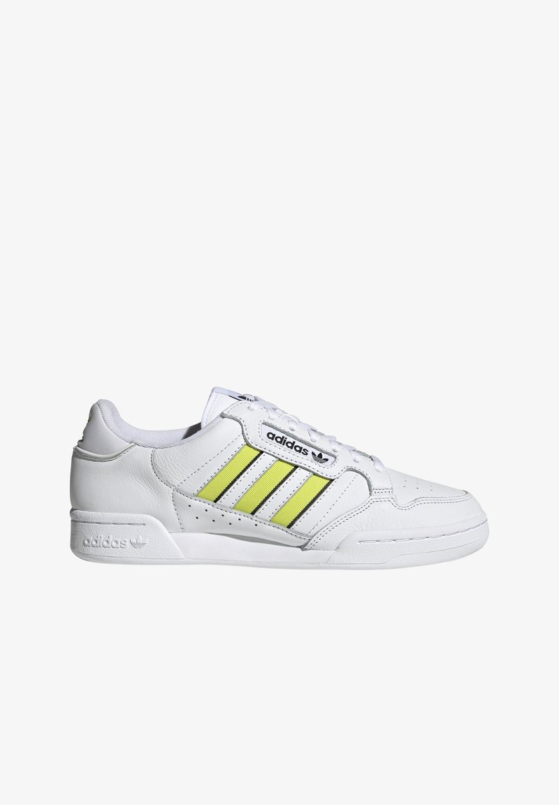 Adidași din piele albă cu trei dungi verticale galbene și negre, detalii perforate pe vârf și talpă din cauciuc. Prezintă logo-ul brandului pe lateral.