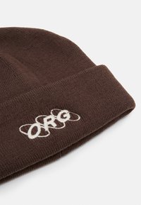 Gorro de malha castanho com dobra, apresentando o logótipo "ORG" bordado em branco. Tecido suave, forma arredondada e detalhe de aba dobrada.