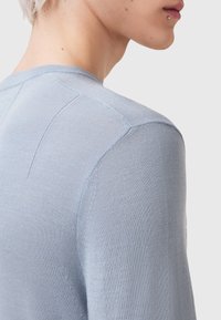 Maglione di colore azzurro chiaro con un design aderente, texture liscia e cuciture dettagliate sulle spalle e sulla schiena.