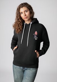 Zwarte hoodie met een voorzak, witte trekkoorden en een cartoon konijnen ontwerp met rode oren. Gemaakt van een zachte, gestructureerde stof.
