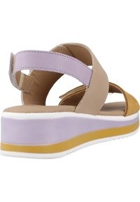 Sandales pour femmes mettant en avant un mélange de matériaux beiges, violets et jaunes. Semelle surélevée avec un intermédiaire blanc. Sangles ajustables pour un meilleur maintien.