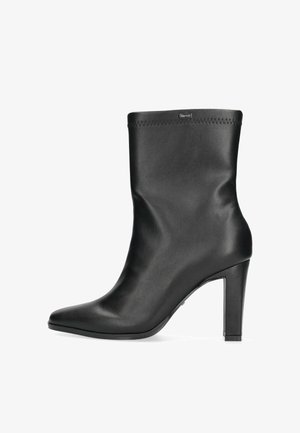 Stivale alla caviglia in pelle nera con punta affusolata, tacco alto sottile e dettaglio di cucitura sul bordo superiore, caratterizzato da una texture liscia e design minimalista.