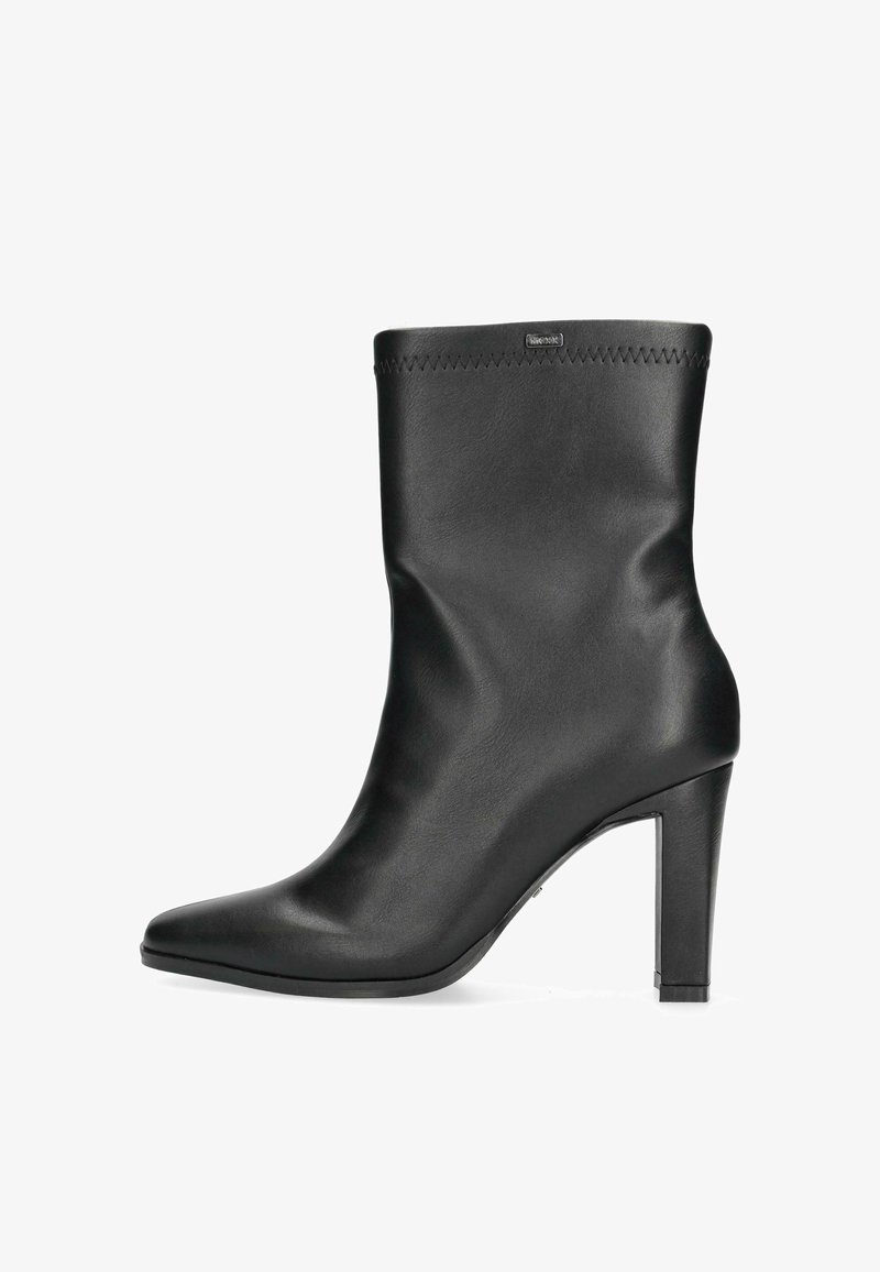 Černá kožená kotníková bota s špičatou špičkou, štíhlým vysokým podpatkem a prošitím na horním okraji, s hladkou texturou a minimalistickým designem.