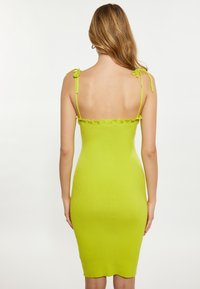 Abito a maglia a costine di un vivace verde lime, con spalline sottili regolabili e scollatura arricciata. Silhouette aderente.