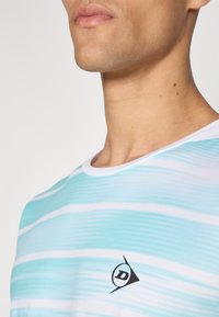 T-Shirt in hellblau mit weißen horizontalen Streifen, Rundhalsausschnitt und einem schwarzen Logo auf der Brust. Glatter Stoff. 