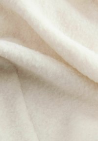 Pehmea, kreemjas värvitoonis kangas, millel on sile, veidi tekstuuriga pind, millel on pehmed voldid ja lained sügavuse loomiseks.