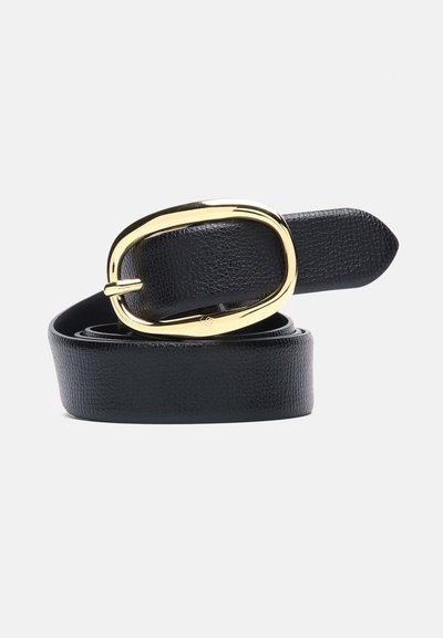 Ceinture en cuir noir roulée avec une grande boucle ovale dorée brillante sur un fond gris clair.