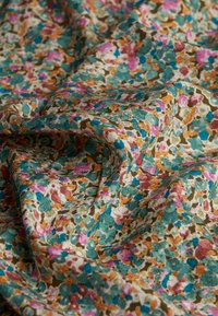 Bloemstof van katoen met een patroon van teal, roze en oranje bloemen op een crèmekleurige achtergrond, met een zachte, gestructureerde val.