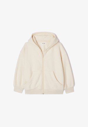 Kreemjas fliisist lukuga pusa ees taskutega, kantud punase särgi peal, kombineeritud mereväe siniste lühikeste pükste, leopardikirjaliste jalanõude ja triibuliste sokkidega.