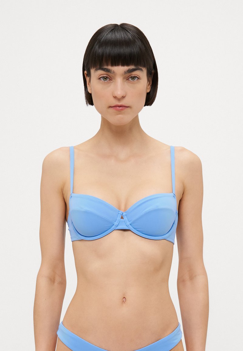 Lyseblå push-up bikini topp med justerbare tynne stropper, underwire støtte og en jevn, glansfull tekstur. Ingen mønstre eller utsmykninger.