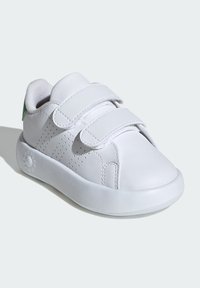 Zapatillas blancas de cuero con dos correas de Velcro, acentos perforados, punta redondeada y suela de goma texturizada. Detalle verde en la parte trasera.