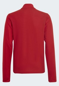 Haut rouge à manches longues avec un motif texturé en diamant, un col montant et un design épuré, fabriqué à partir d'un tissu lisse et léger.