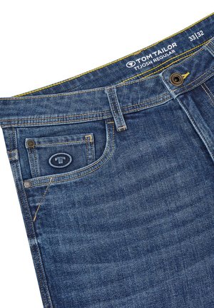 Denim-Jeans in Mittelblau mit regulärer Passform. Merkmale umfassen eine Vordertasche, kontrastierende gelbe Nähte und ein Markenetikett am Bund.