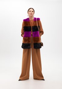 Faux fur vest with purple, brown, and black stripes; paired with a brown top and wide-leg brown pants; features chunky earrings and a chain bag.