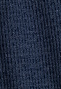 Marineblaue gerippte Stoff mit feinen vertikalen Linien, der eine weiche Textur und ein gleichmäßiges Muster über das Material hinweg zeigt.