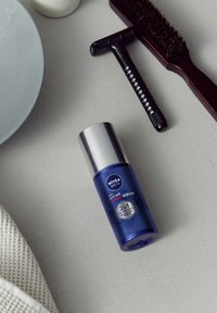 Nivea Men Anti-Age Power Serum in einer blauen Plastikflasche mit silberner Kappe, mit auffälligem weißem und rotem Text sowie einem Etikett, das 2-in-1 angibt.