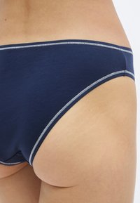 Εσώρουχο από βαμβάκι σε ναυτικό μπλε με απαλό ύφασμα και αντίθετες γκρι ραφές κατά μήκος των άκρων. Σχεδιασμένο με χαμη λή μέση, χωρίς ορατά σχέδια.