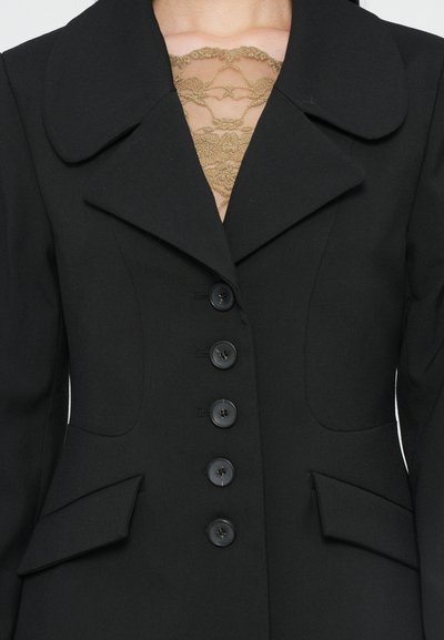 Black blazer with large lapels, a fitted design, six button closures, and side pockets; lace detail is visible at the neckline.