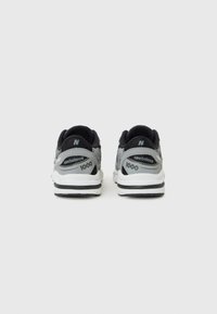 Baskets New Balance noires et grises avec une semelle rembourrée, une forme arrondie, une texture en maille et des accents de logo sur le talon et le côté.