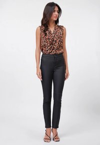 Bezrokuļa tops ar leoparda rakstu un drapētu v-veida izgriezumu, kopā ar melnām pieguļošām biksēm. Modele valkā melnas sandales ar papēdi.