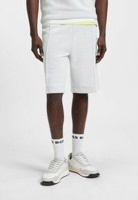 Witte geperforeerde shorts met een slim fit, voorzien van contrasterende gele voering aan de taille en subtiele zijnaaddetails. G gedragen met witte sneakers.