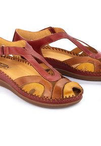 Leren sandalen met rode, bruine en gele tinten en een open teen ontwerp. Stiksel langs de randen en verstelbare banden.