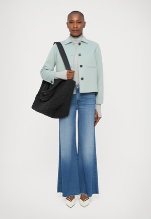 Veste bleu clair, col roulé gris, sac matelassé noir, jean bleu évasé, chaussures blanches à bout pointu. Textures distinctives et lignes épurées.