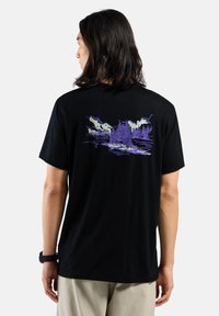 Schwarzes Baumwoll-T-Shirt mit einem lila, naturinspirierten Grafikdesign auf der Rückseite, das Bäume und Berge vor einem Wasserhintergrund darstellt.