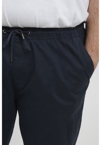 Marineblauwe shorts van lichtgewicht materiaal, met een elastische tailleband met trekkoord, zijzakken en een zachte textuur.