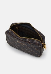 Brun Guess-påse med guldlogotyper, guldblixtlås, öppen topp som visar det inre fack med blixtlås och tygfoder.