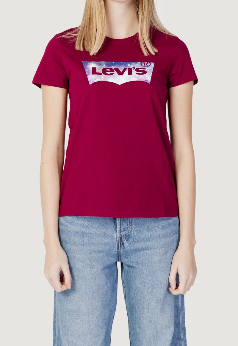 Maroon cotton t-shirt featuring a large Levi's logo in a galaxy design. Crew neck, short sleeves, paired with light blue wide-leg jeans.