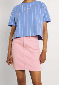 Ljusblå kort t-shirt med vertikala vita och rosa ränder; kombinerad med en rosa jeanskjol med en figursydd design och framfickor.