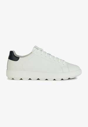 Baskets blanches en cuir lisse avec une accent noir au talon, présentant un bout rond, un système de laçage et une semelle en caoutchouc épaisse aux bords arrondis.