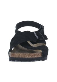 Sandalias de ante negro con plantilla de corcho, que cuentan con dos tiras anchas, una tira trasera y un hebilla ajustable. Suela plana de goma.