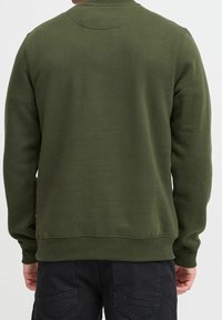 Donkere groene sweatshirt met een geribbelde halslijn en manchetten. Heeft een soepele textuur en een minimalistisch ontwerp, zonder zichtbare patronen of details.
