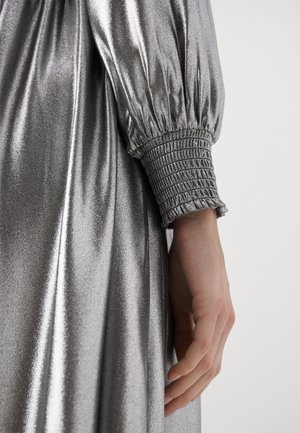 Glänzendes silbernes Kleid mit Puffärmeln und gerüschten Manschetten sowie einer glatten, reflektierenden Textur, die die drapierten Stoffdetails zur Geltung bringt.
