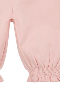 Pantaloni di tessuto rosa con polsini arricciati ed elasticizzati alle caviglie, che mostrano cuciture dettagliate e una texture morbida.
