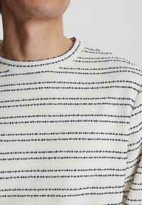 Pulover de culoare crem cu dungi orizontale albastre, țesătură texturată, guler rotund cu bordură și detalii în model punctat pe întreaga suprafață.