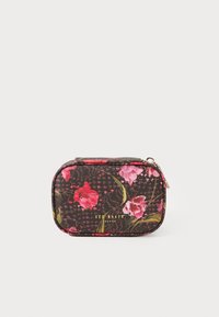 Neceser compacto de Ted Baker con fondo negro, patrón floral en tonos rosas, hojas verdes y tirador de cremallera en color dorado.