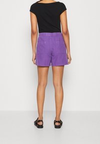 Lila shorts med elastisk midja och två bakfickor. Matchat med en svart kortärmad topp och svarta sandaler.