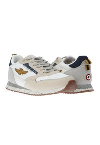 Sneaker con parte superiore in mesh beige e bianca, dettagli in suede grigio, suola maculata marrone, logo ricamato e particolare colorato sul tallone posteriore.